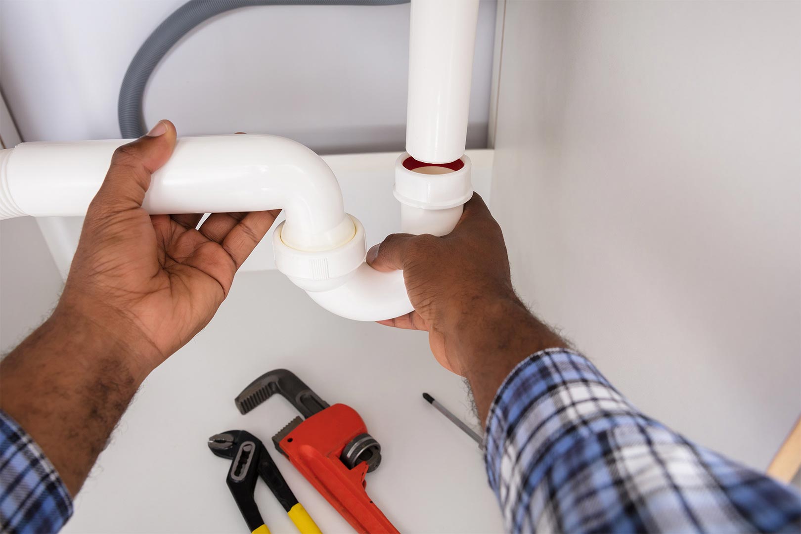hands of plumber attaching white pipe ontario ca